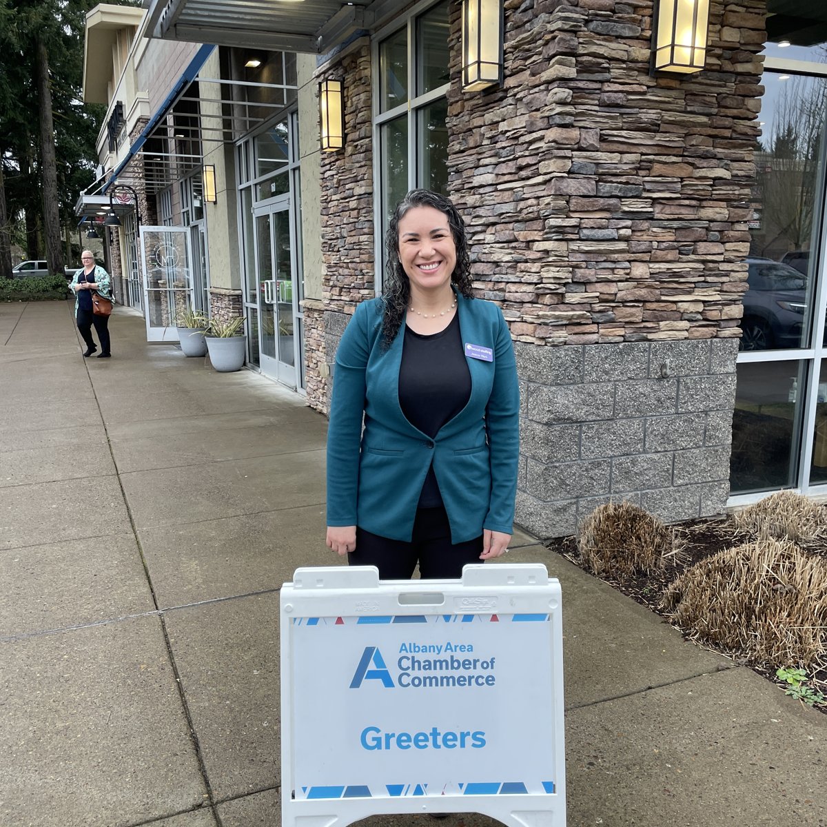 Jessica Wark behind an Albany Area Chamber of Commerce greeters sign
